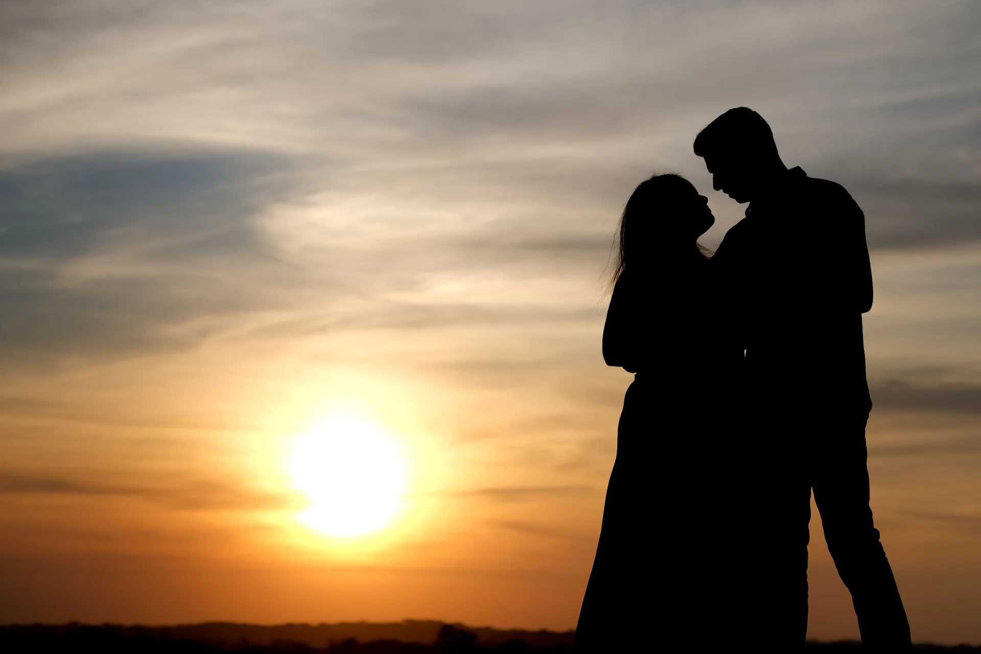 Couple silhouetted against a sunset during a pre-wedding shoot.