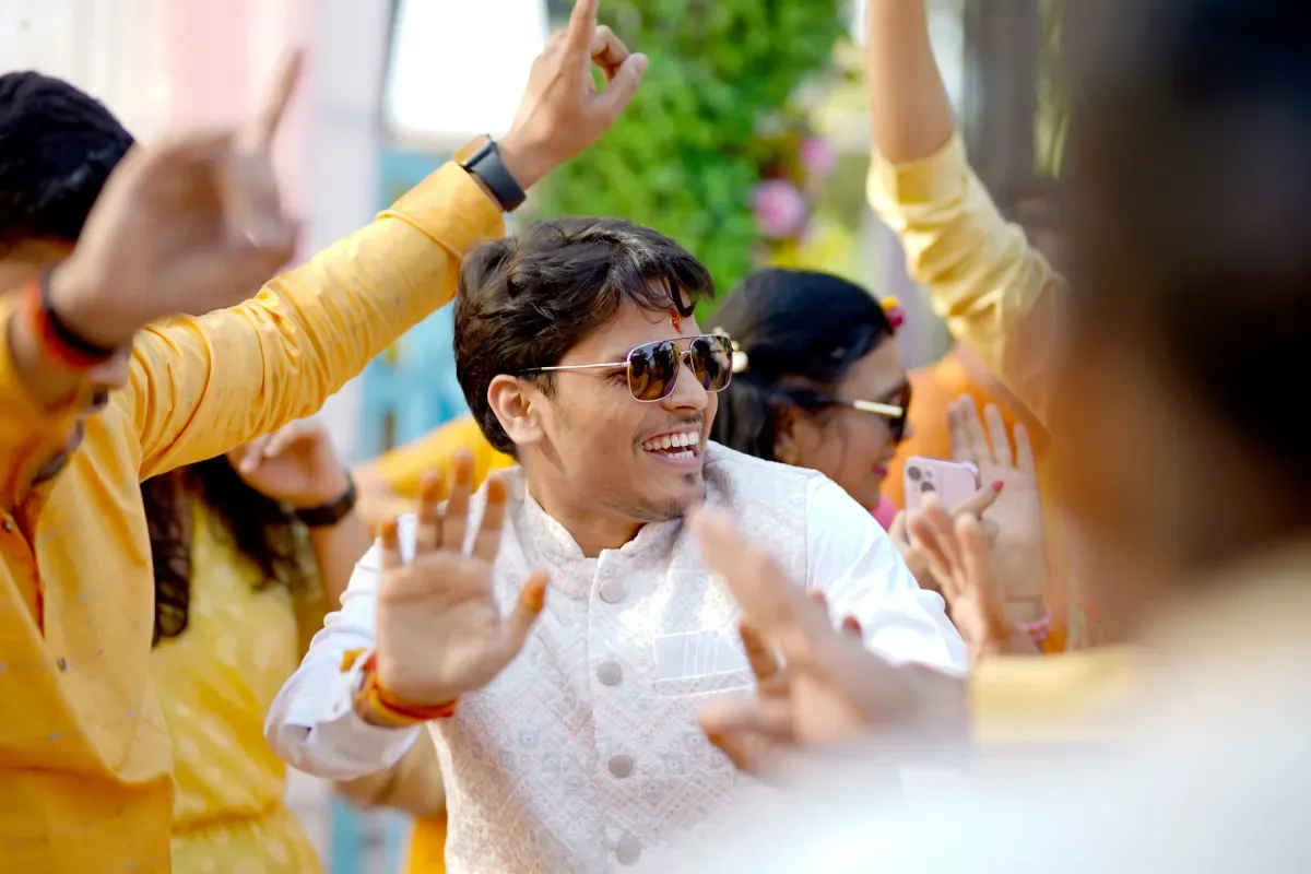 A joyful man dancing in traditional attire during a wedding celebration.