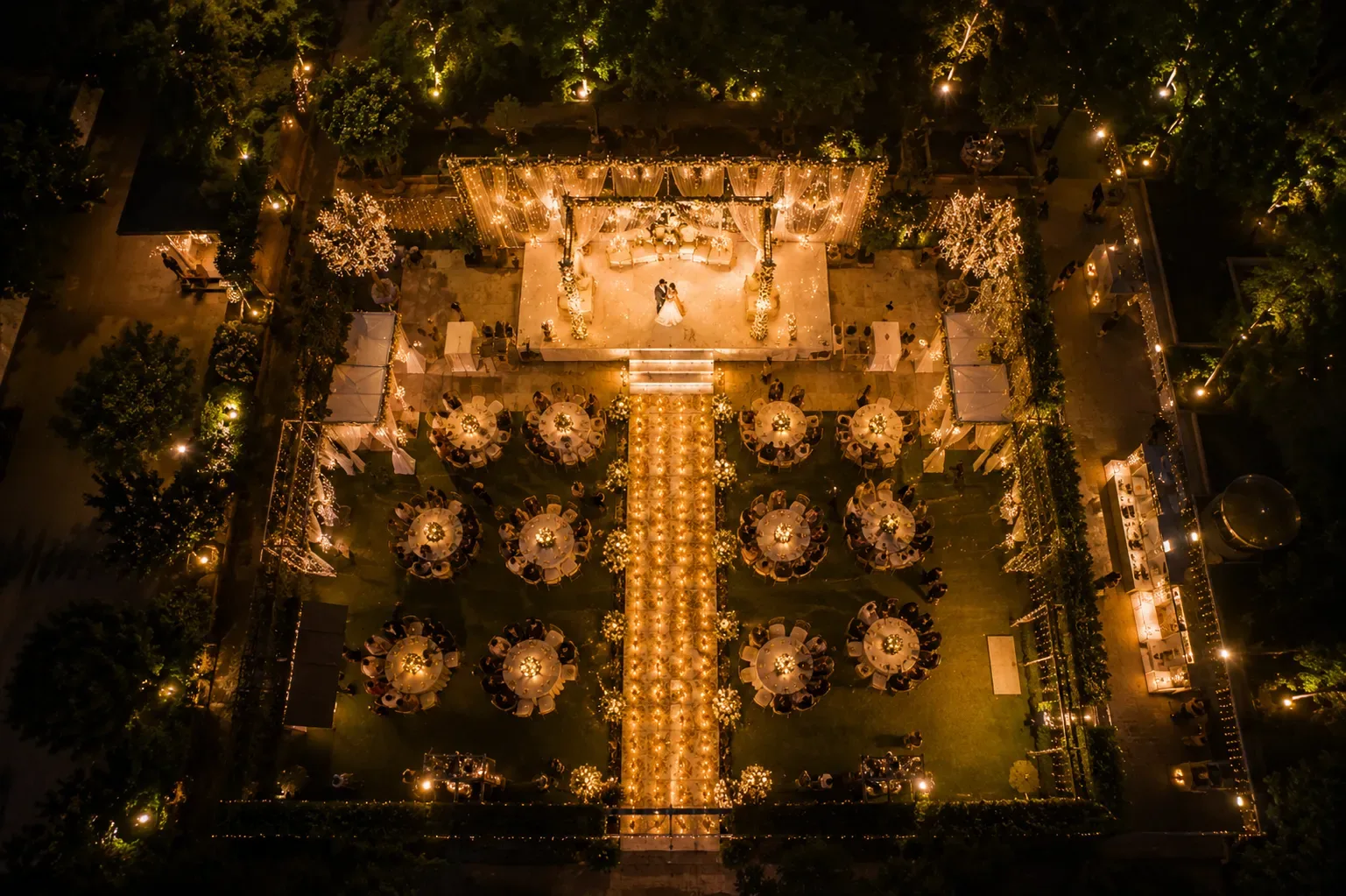 Aerial view of a beautifully decorated wedding reception with tables and lights